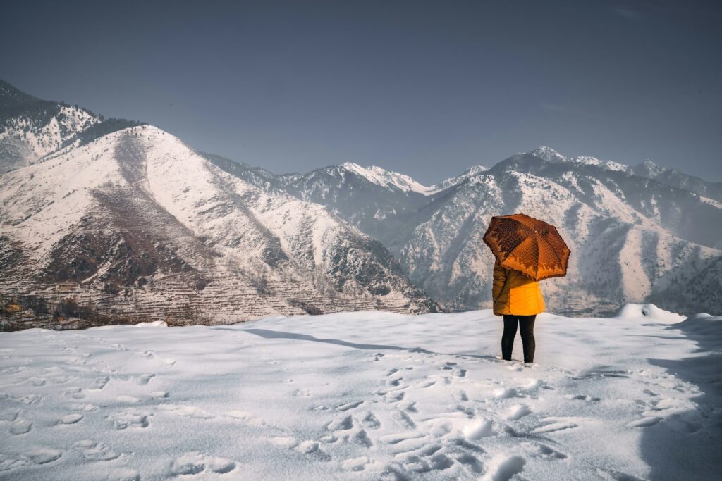 person in orange jacket standing on snow covered ground during daytime