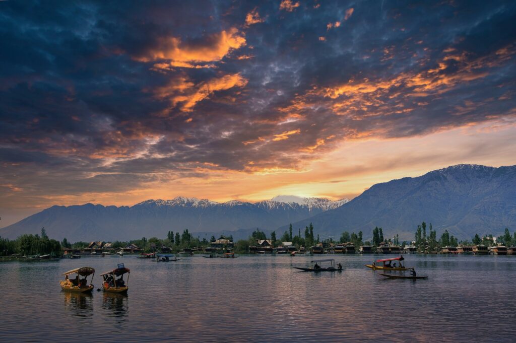 a group of boats floating on top of a lake under a cloudy sky