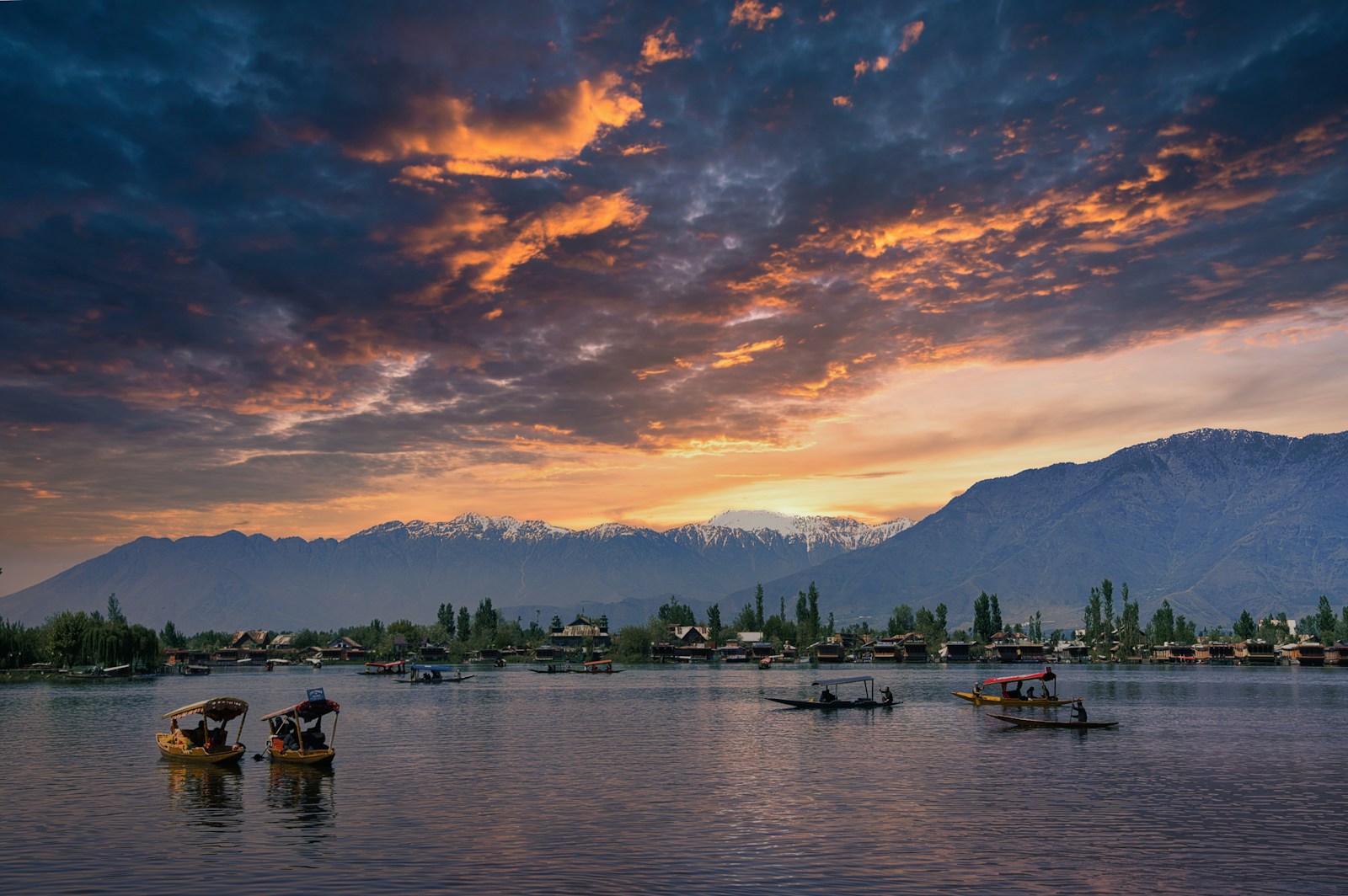 a group of boats floating on top of a lake under a cloudy sky