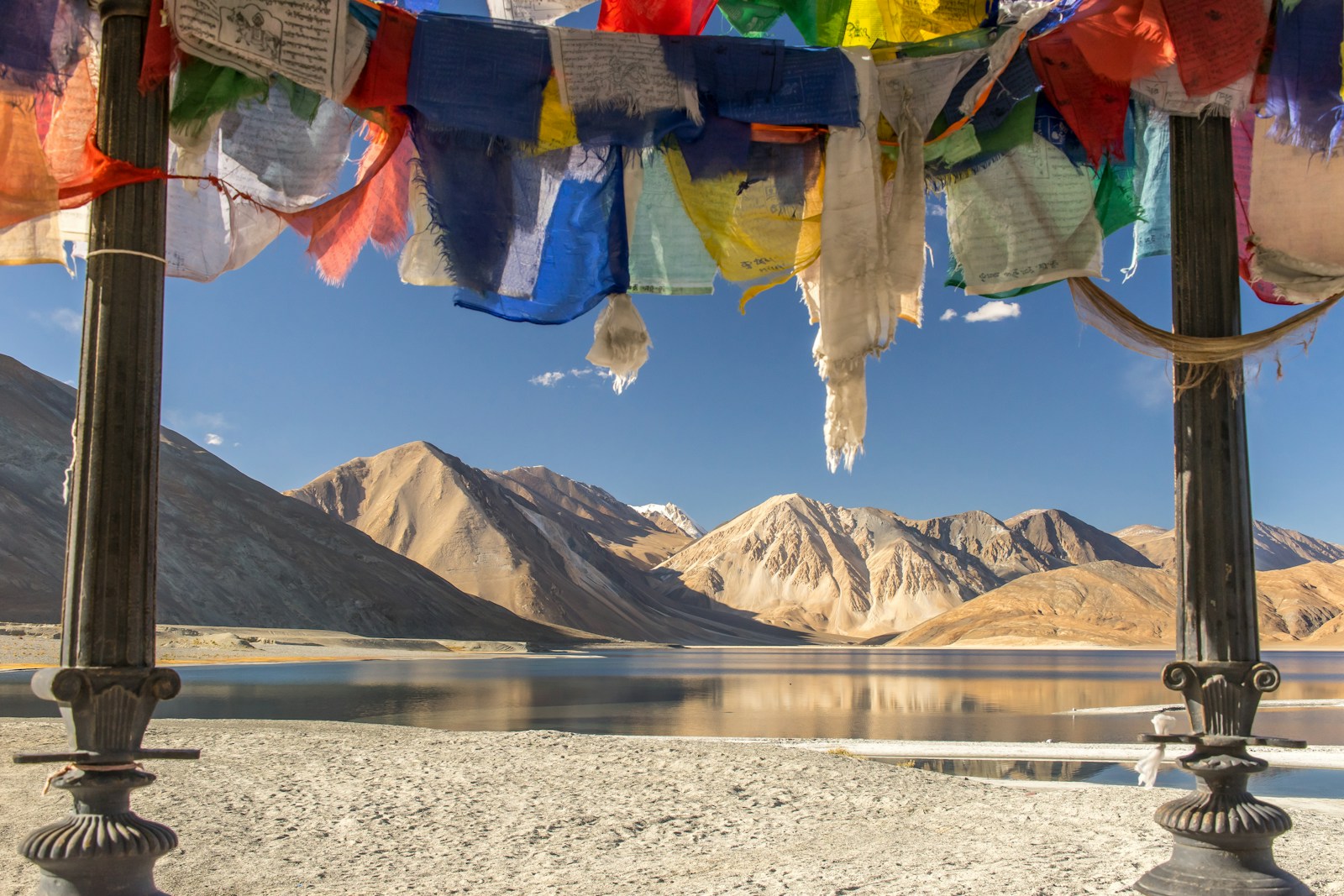 blue yellow and red textile on gray sand near lake and mountain during daytime